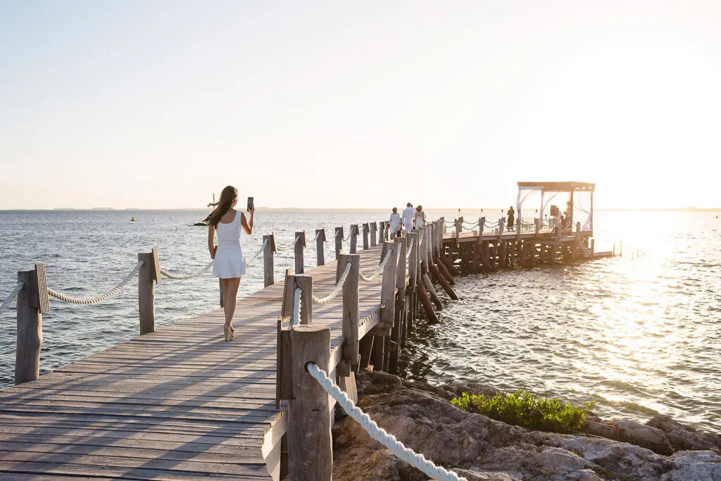 Romantic sunset wedding pier in Riviera Maya Mexico with bride walking wooden boardwalk over turquoise Caribbean waters