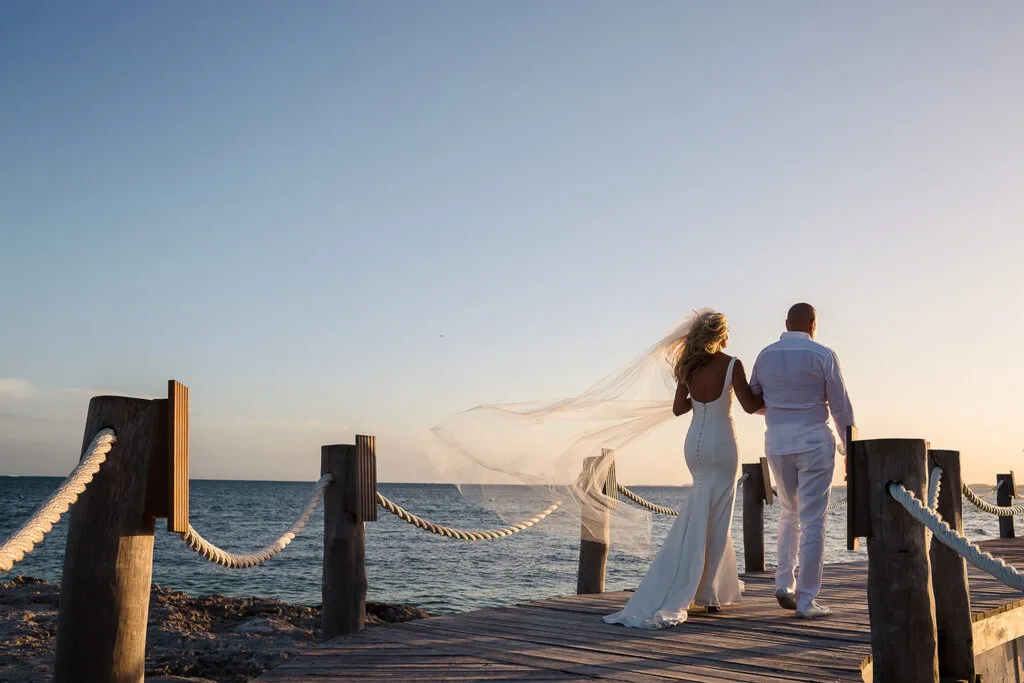 Bride and groom walking on wooden dock at sunset in Cancun Mexico destination wedding photography Riviera Maya