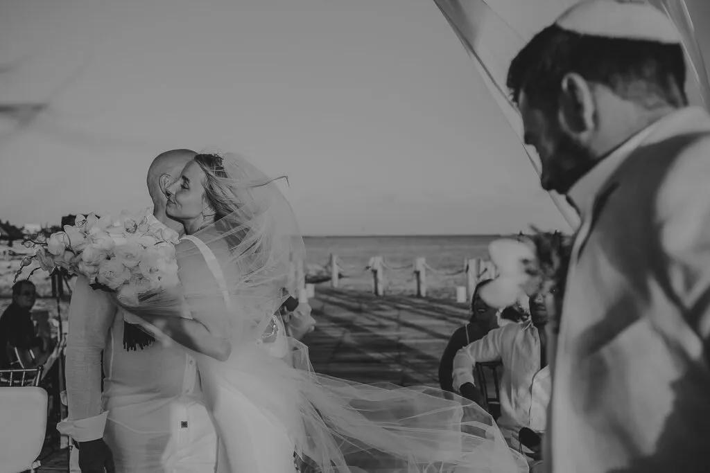 Bride and groom embracing on yacht deck in Cancun with ocean views, romantic destination wedding photography in Riviera Maya