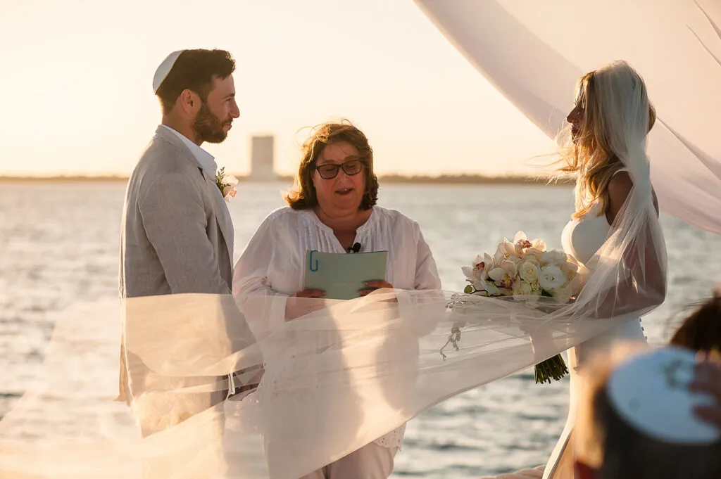 Beach wedding ceremony in Cancun with couple exchanging vows at sunset officiated by minister overlooking Caribbean Sea