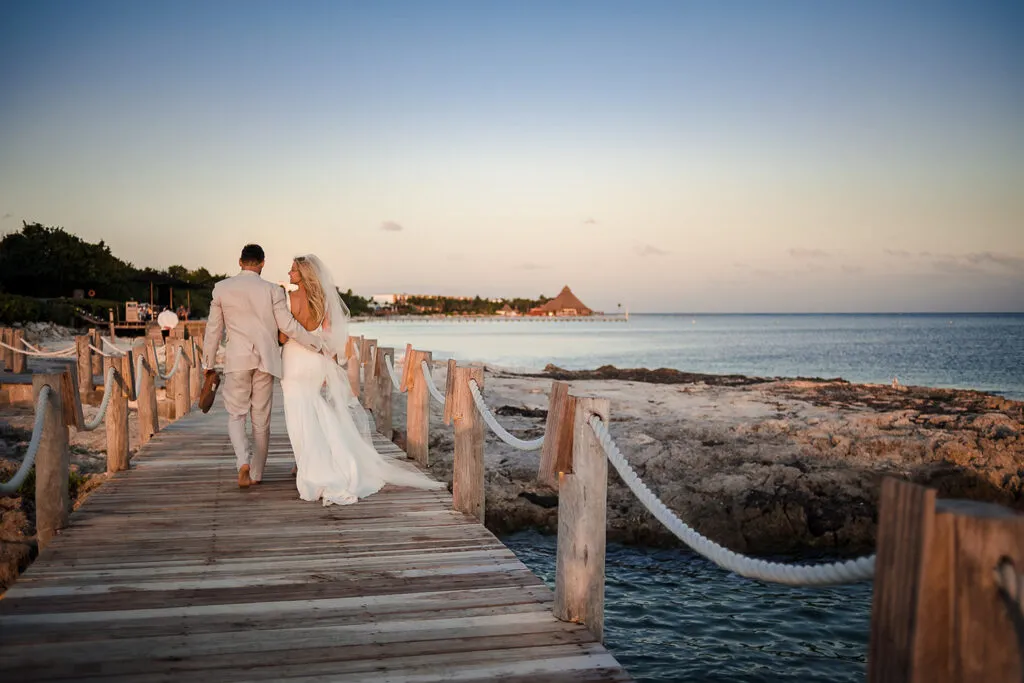 Bride and groom walking on wooden pier at sunset in Riviera Maya Mexico destination wedding photography session