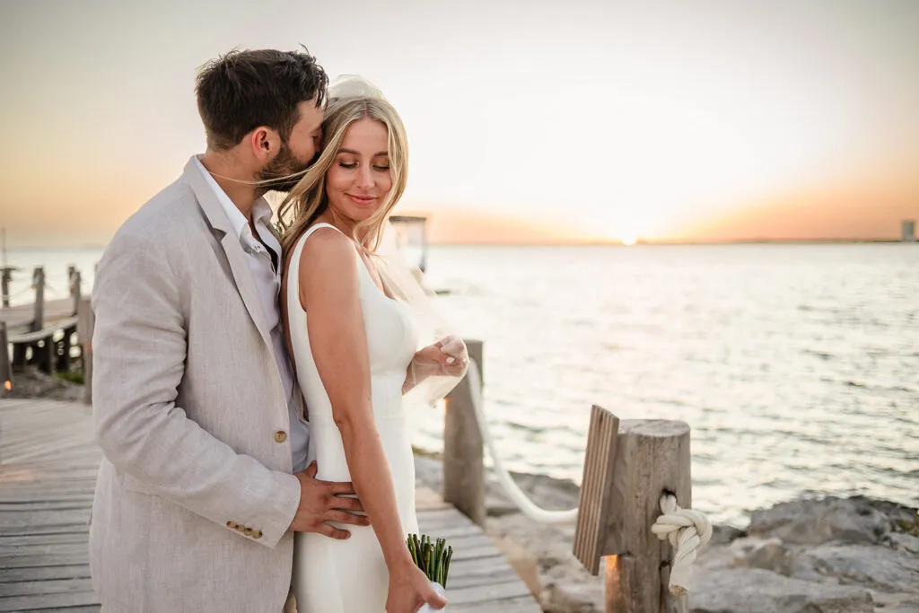 Romantic sunset wedding couple embracing on wooden dock in Riviera Maya Mexico destination wedding photography