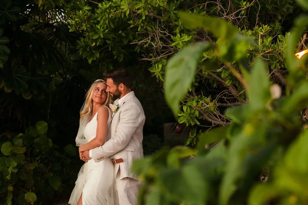 Romantic bride and groom embrace in lush tropical jungle setting during Riviera Maya destination wedding photography session