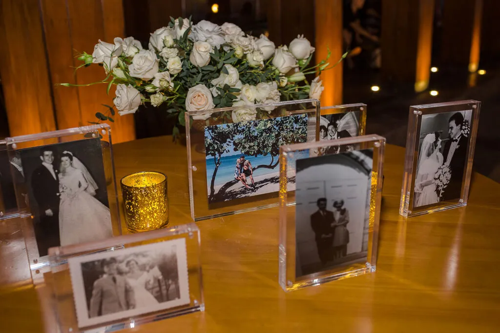 Wedding photo display with acrylic frames showing couple memories at Cancun Riviera Maya reception centerpiece with white roses