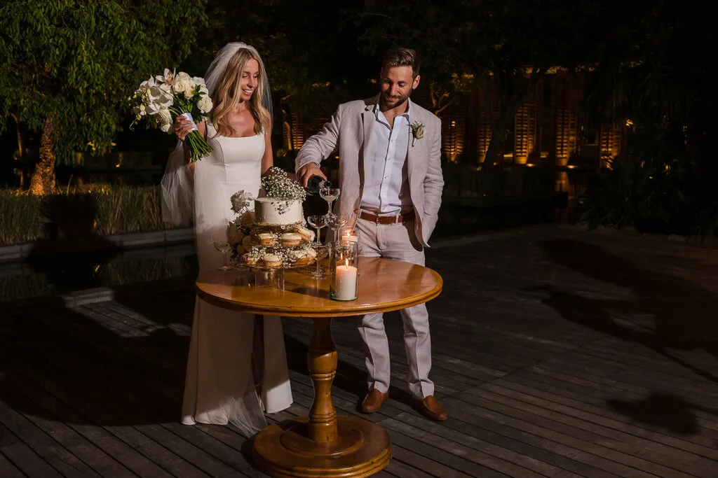 Newlyweds cutting wedding cake at romantic evening reception in Cancun Riviera Maya Mexico destination wedding photography