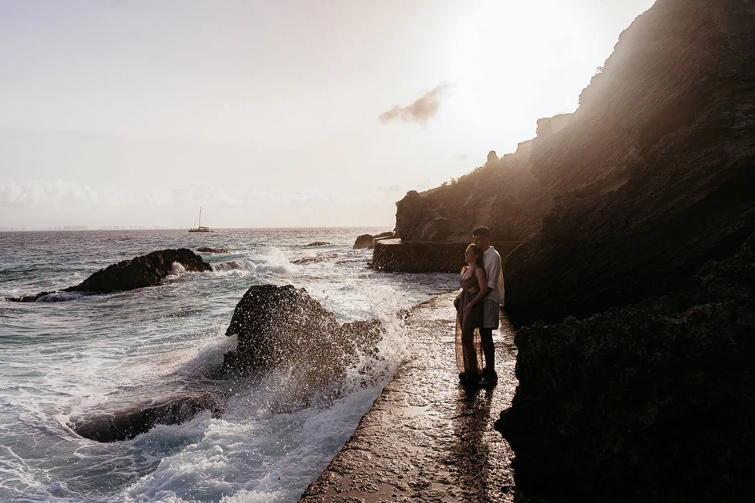 Romantic couple embracing at sunset on rocky coastline in Riviera Maya Mexico during engagement photo session