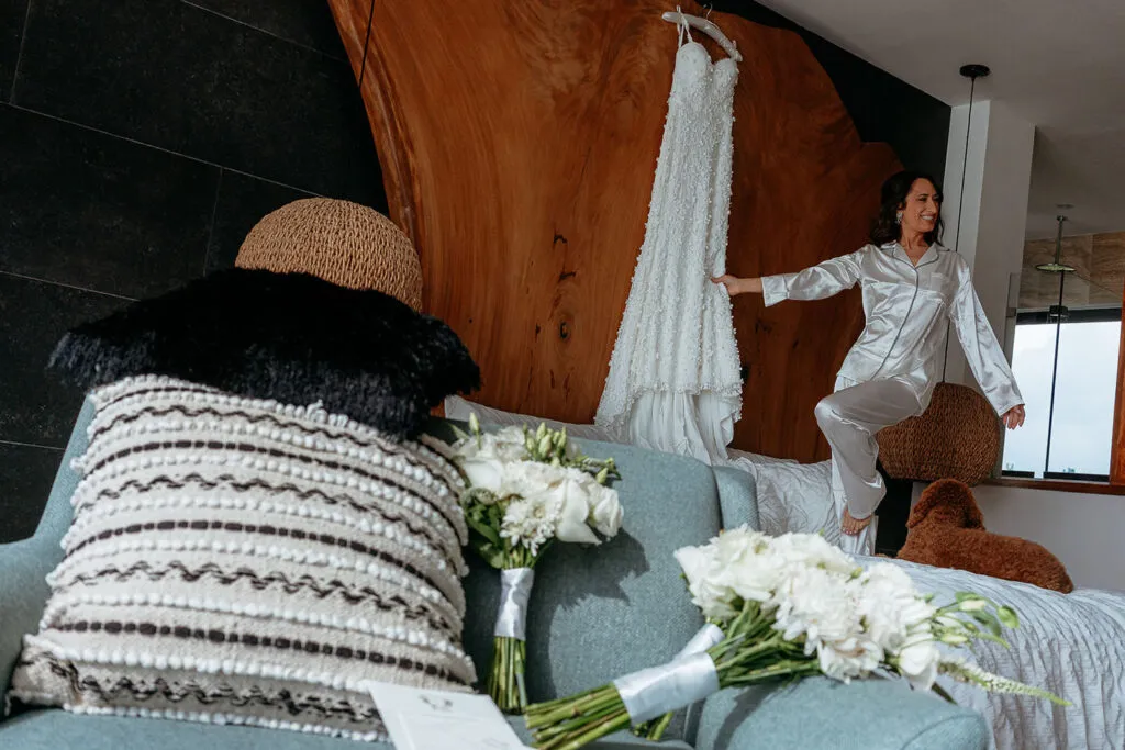 Bride in silk pajamas admiring wedding dress during getting ready photos at luxury Cancun resort bridal suite