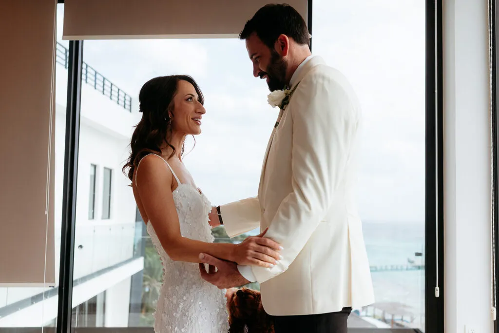 Bride and groom intimate moment by window during Cancun wedding ceremony with ocean view in Riviera Maya Mexico