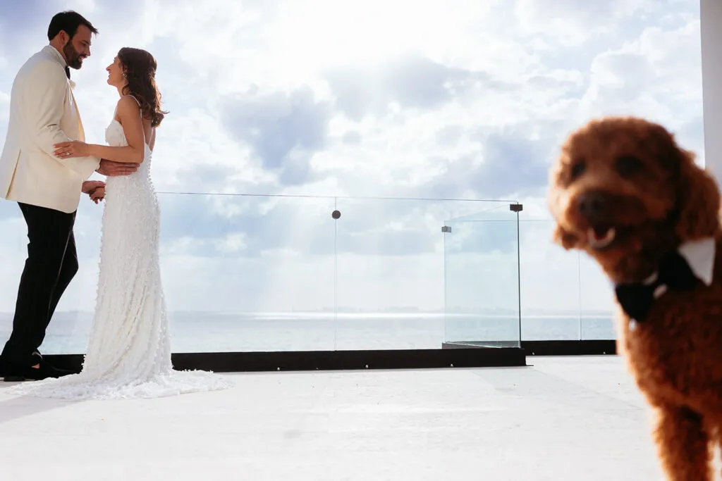 Bride and groom embrace on oceanfront terrace with Caribbean Sea views during Riviera Maya destination wedding ceremony
