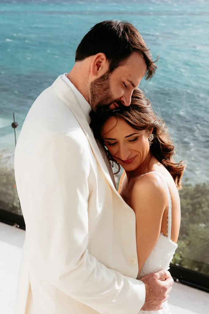 Romantic beach wedding couple embracing at luxury Riviera Maya resort with turquoise Caribbean Sea backdrop in Cancun Mexico