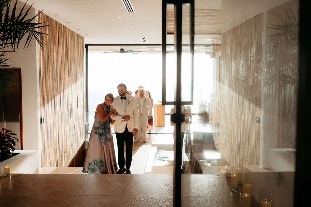 Groom walking down aisle with family at luxury Cancun wedding venue with modern architecture and ocean views