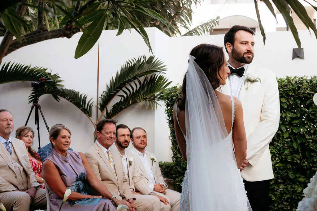 Bride and groom exchange vows at tropical Cancun wedding ceremony with palm trees and guests in Riviera Maya Mexico