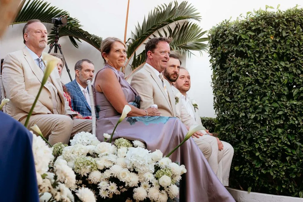 Wedding guests in elegant attire at outdoor Cancun ceremony with tropical palms and white flowers in Riviera Maya Mexico