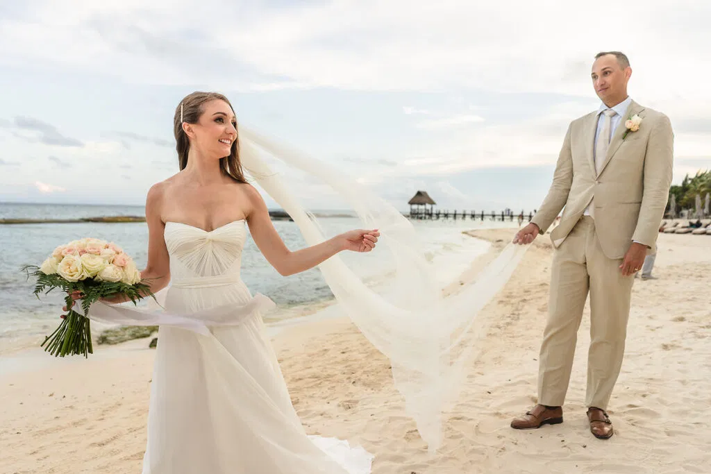 Bride and groom holding hands on cancun beach with flowing veil, turquoise Caribbean Sea Micro wedding cancun