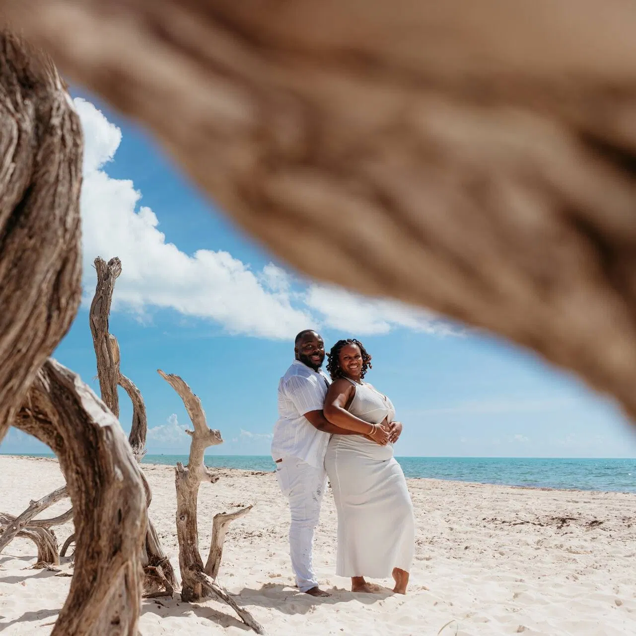 Romantic couples photoshoot on pristine Isla Blanca beach with driftwood, perfect for destination proposals in Cancun