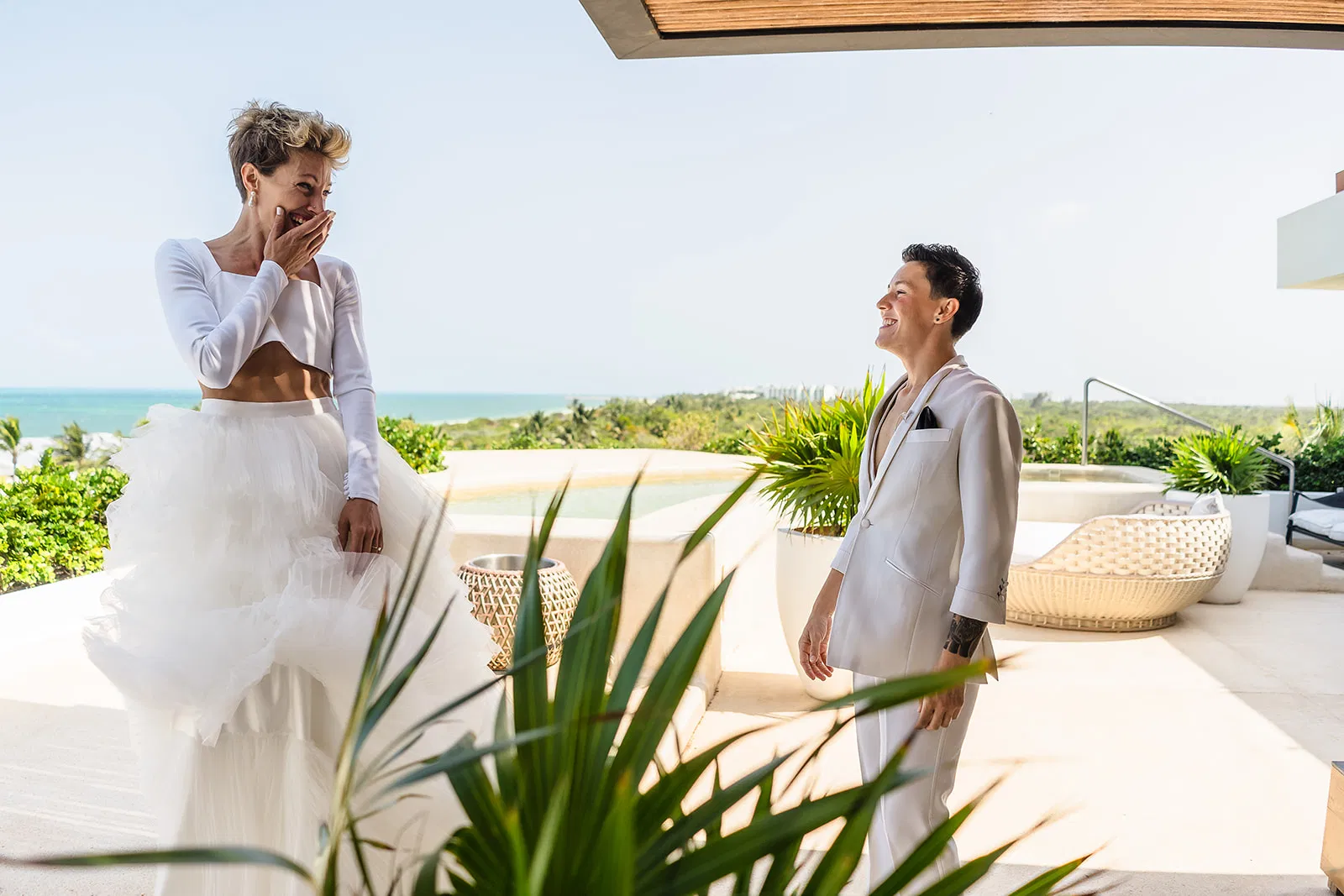 LGBTQ couple celebrating wedding proposal on luxury resort terrace overlooking Caribbean Sea in Riviera Maya Mexico