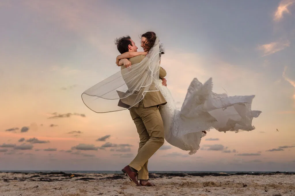 Romantic couple spinning on Tulum beach at sunset - destination wedding photography capturing pure joy and love