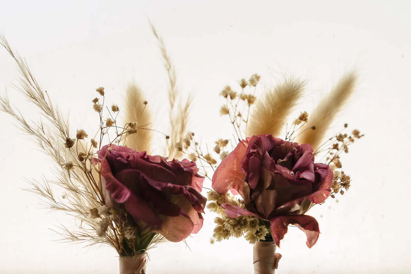 Dried flower boutonnieres with burgundy roses and pampas grass for same-sex wedding at Blue Venado Riviera Maya