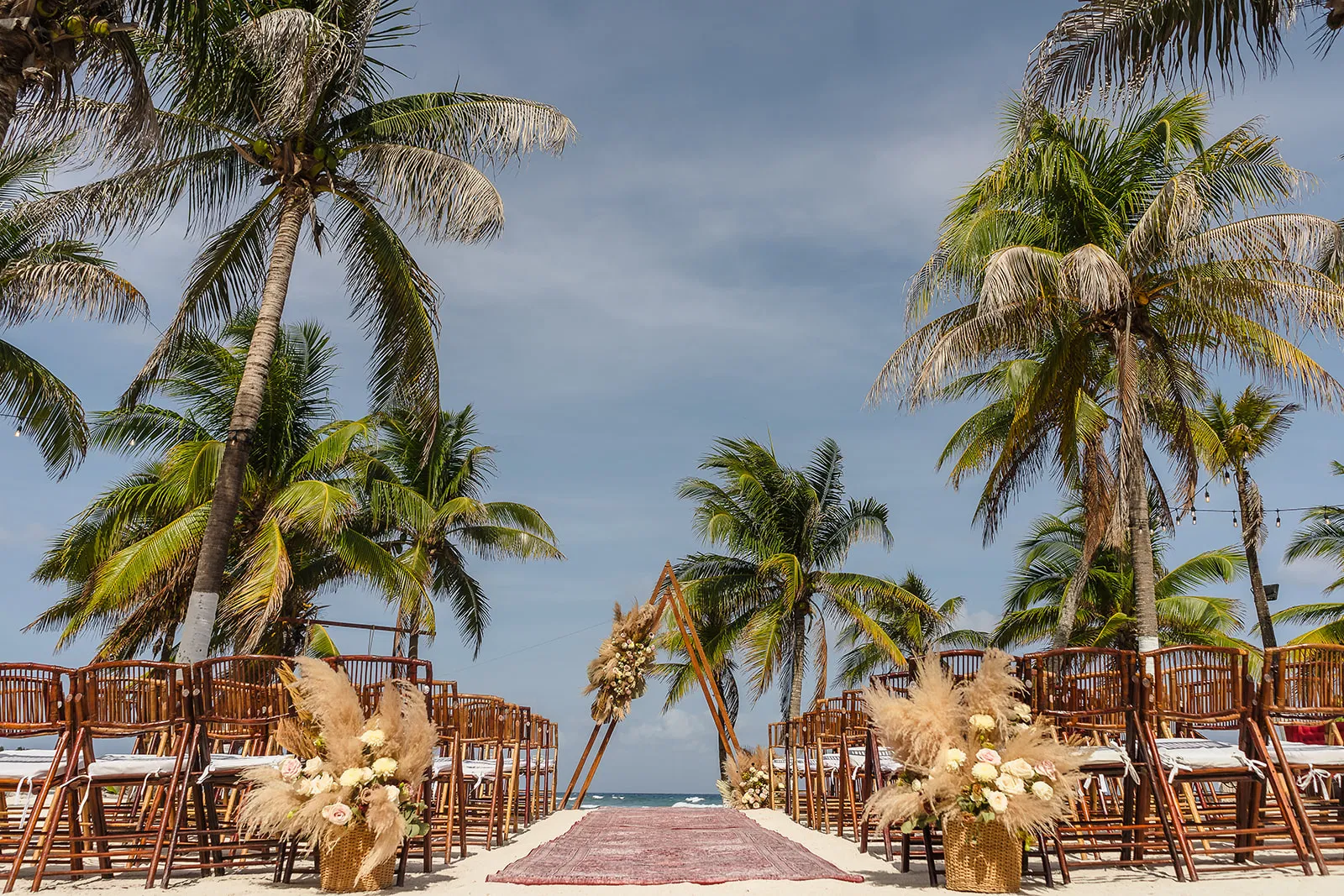 Beach wedding ceremony setup with palm trees and pampas grass at Blue Venado in Riviera Maya by Tam Rico Photo