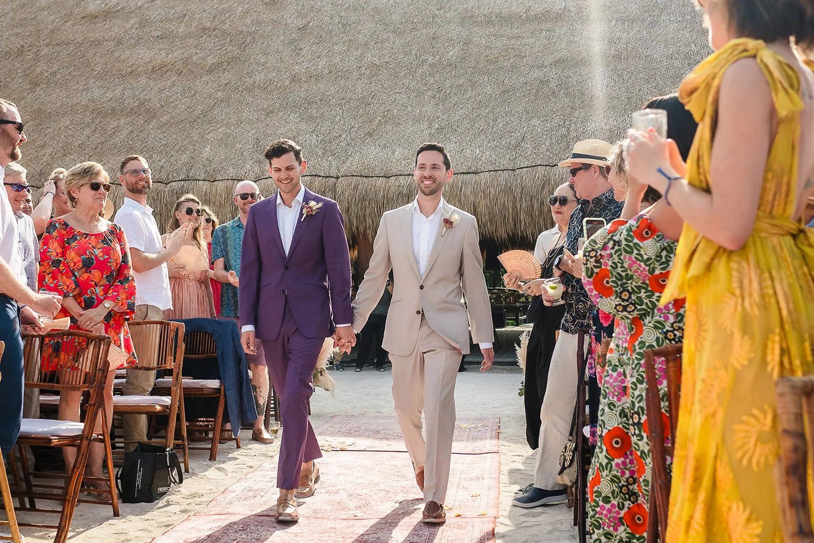 Two grooms walking down the aisle hand in hand at their Blue Venado beach wedding in Riviera Maya by Tam Rico Photo