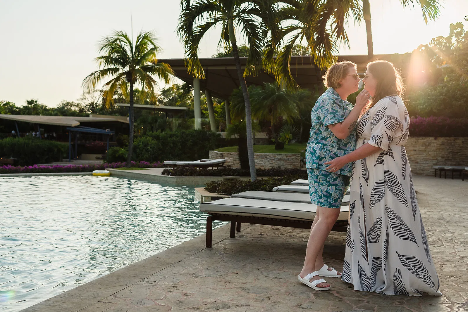 LGBTQ couple embracing at sunset by pool at Rosewood Mayakoba, Riviera Maya same-sex wedding photography Mexico