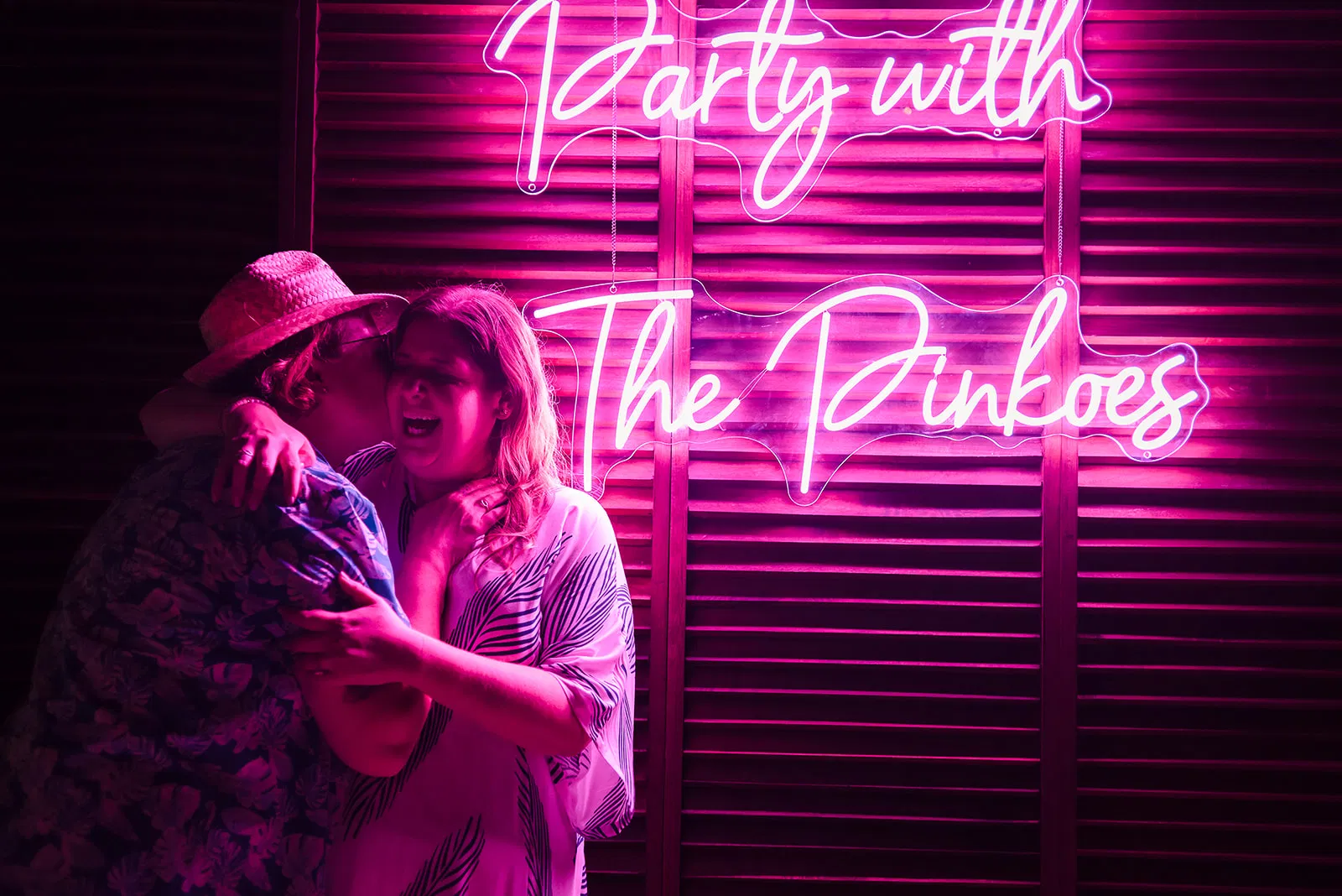 LGBTQ couple embracing under neon sign at Rosewood Mayakoba, romantic same-sex wedding photography in Cancun Riviera Maya Mexico