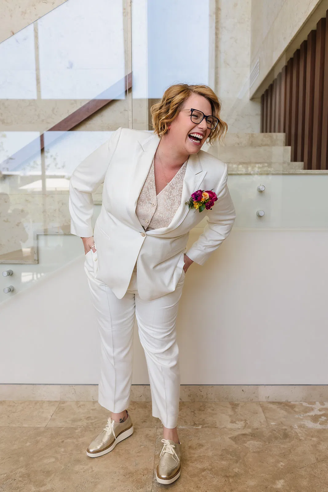 LGBTQ bride in white suit laughing joyfully at Rosewood Mayakoba same-sex wedding in Riviera Maya Mexico destination ceremony