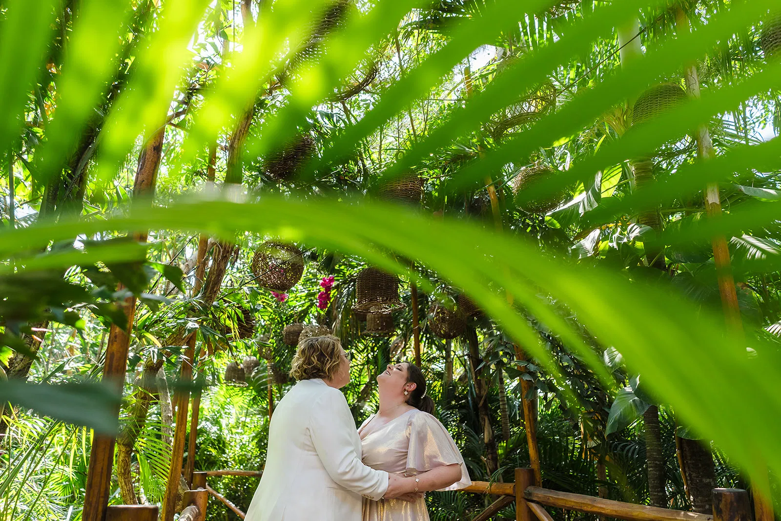 LGBTQ couple in white dresses share intimate moment in tropical jungle at Rosewood Mayakoba Riviera Maya Mexico same-sex wedding