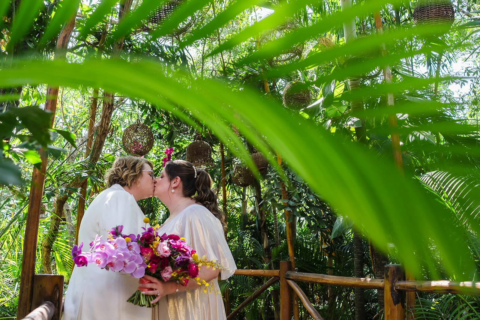 Same sex wedding, two brides kissing in a tropical deck at Rosewook Mayacoba