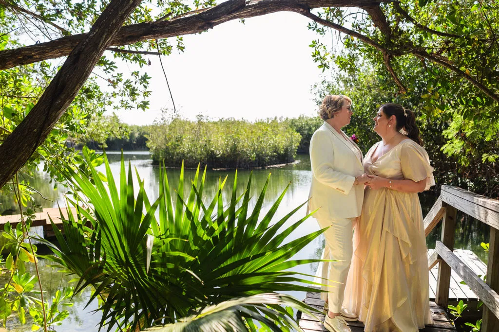 Same-sex wedding couple embracing on wooden dock at Rosewood Mayakoba, LGBTQ destination wedding photography Riviera Maya Mexico