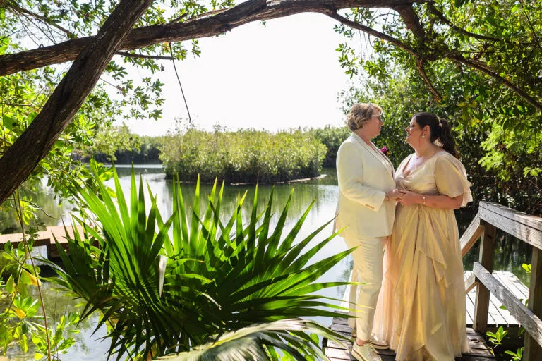 Same-sex wedding couple embracing on wooden dock at Rosewood Mayakoba, LGBTQ destination wedding photography Riviera Maya Mexico