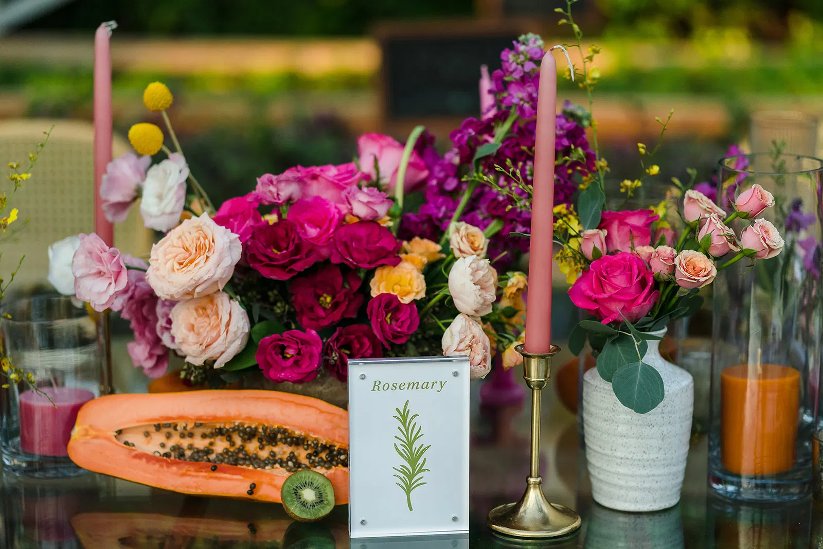 LGBTQ wedding centerpiece with vibrant flowers, candles, and tropical fruits at Rosewood Mayakoba same-sex celebration