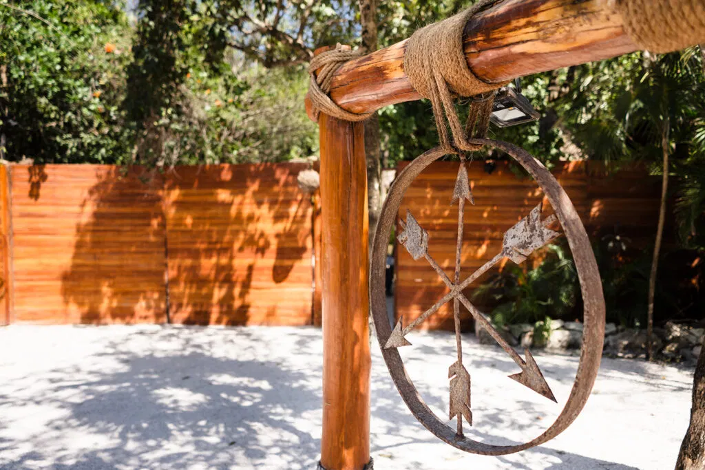 Rustic wooden wedding arch with compass rose detail at Tulum beach ceremony venue, Mexico destination wedding photography