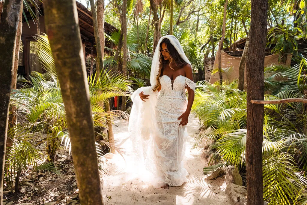 Bride in lace wedding dress walking through tropical jungle path in Tulum Mexico destination wedding photography