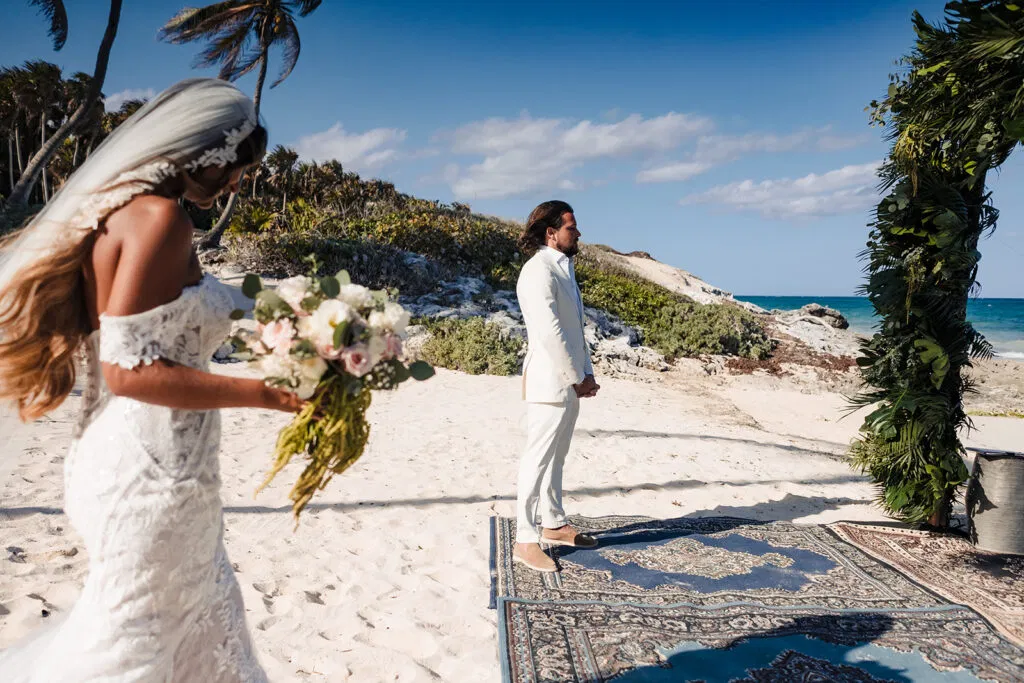 Bride and groom beach wedding ceremony in Tulum Mexico with tropical palm trees and turquoise Caribbean ocean backdrop