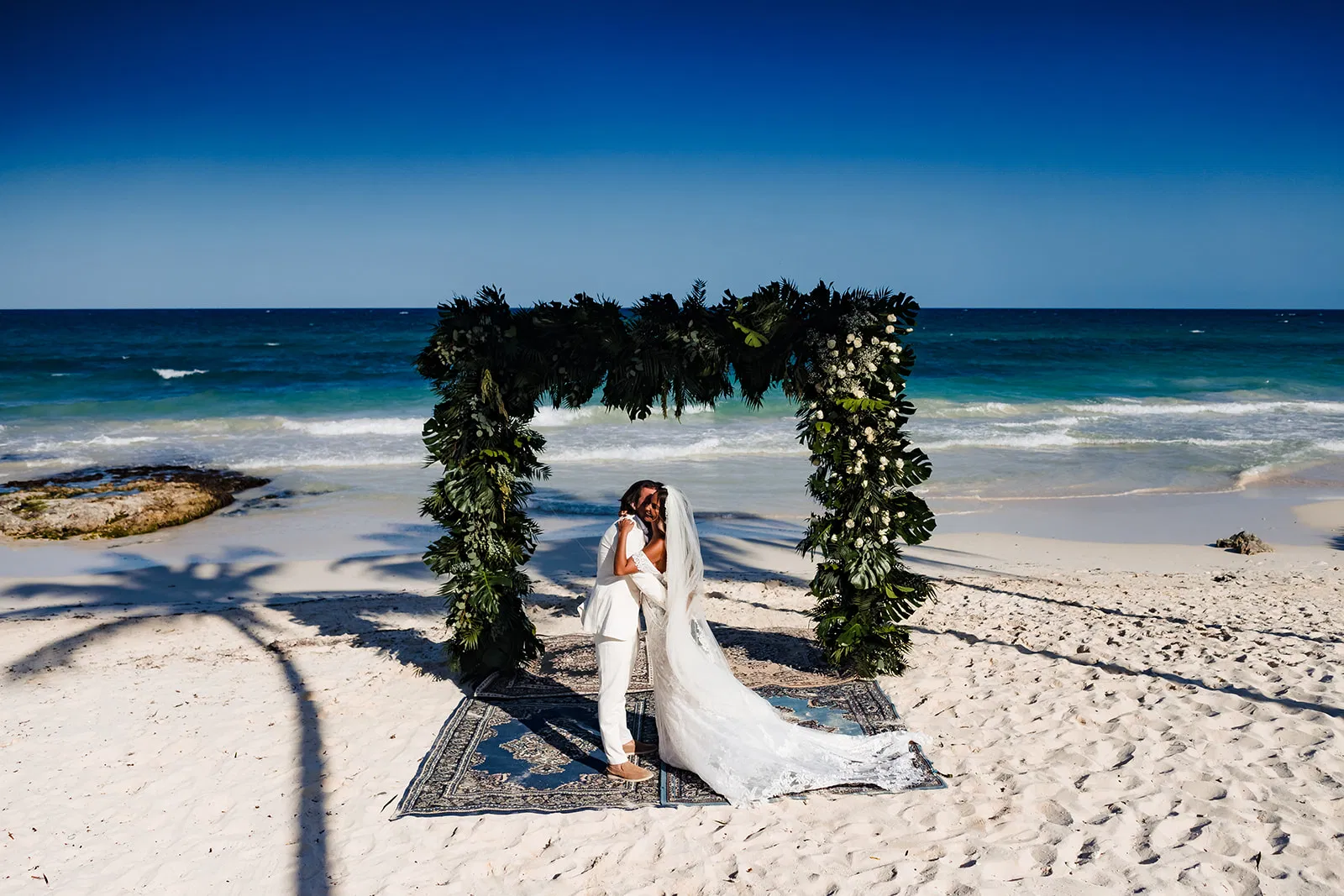 Romantic beach wedding ceremony in Tulum Mexico with tropical arch and turquoise Caribbean Sea backdrop for couples