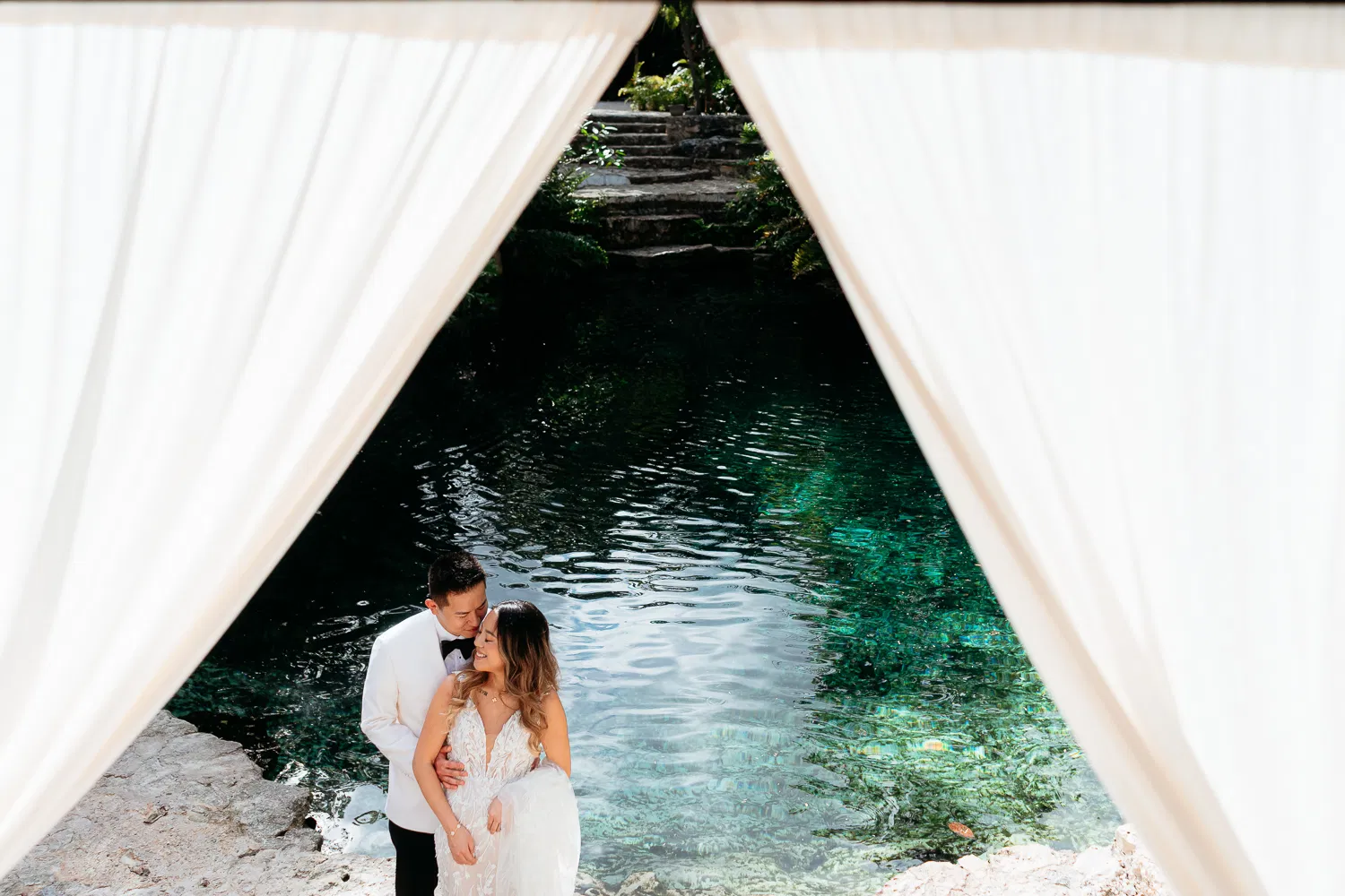 Romantic bride and groom embracing under cenote archway in Tulum Mexico for destination wedding photography session