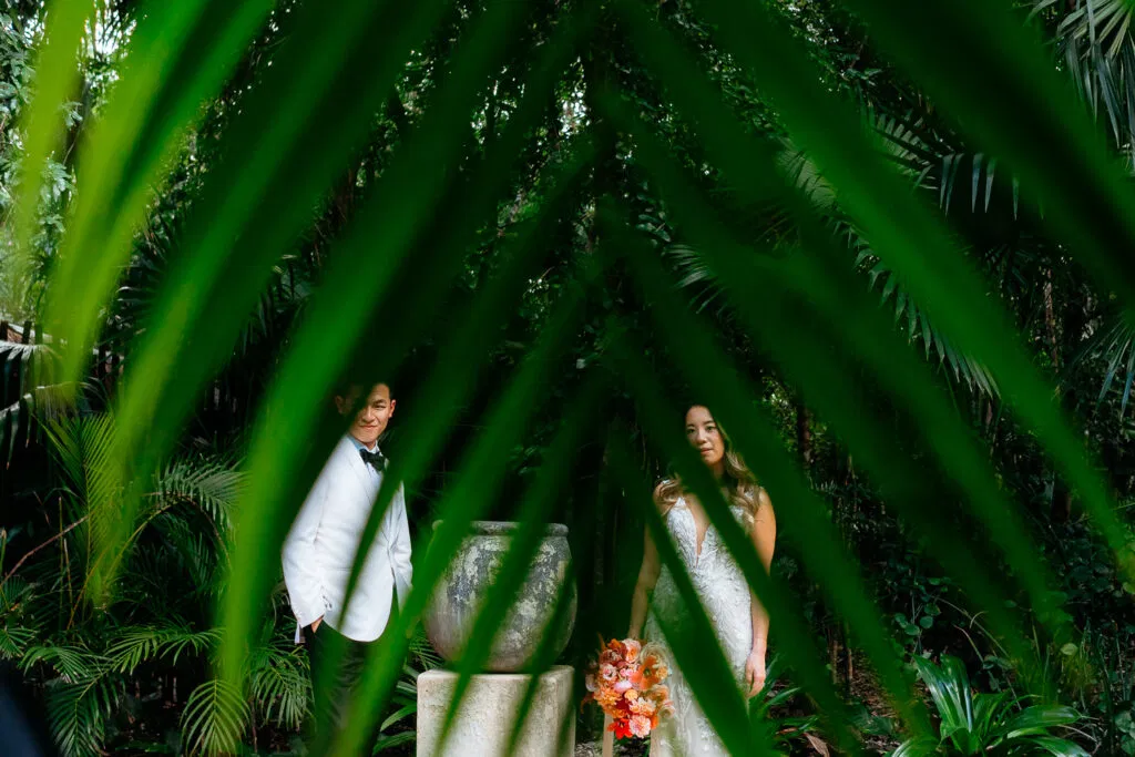 Bride and groom in tropical jungle wedding photo shoot among lush palm trees in Tulum Mexico destination wedding photography