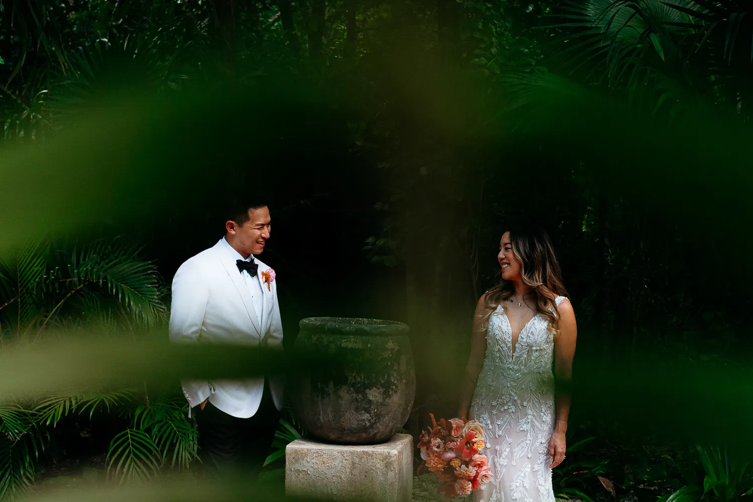 Bride and groom in tropical Tulum wedding photography session surrounded by lush jungle greenery and stone architecture