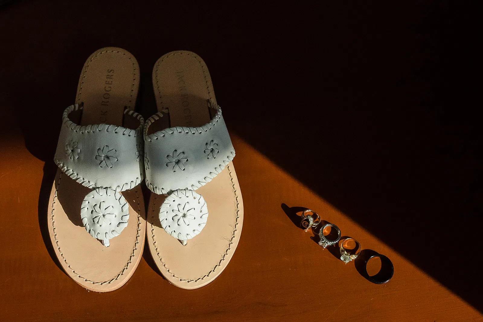Bride's white leather sandals and wedding rings on orange surface for Tulum Mexico destination wedding photography
